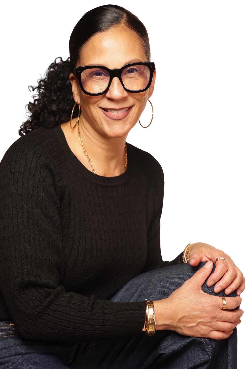 Portrait of Dr. Cara, smiling, wearing black glasses and a black sweater with gold jewelry.